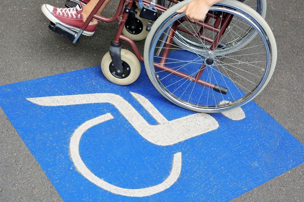 Frau mit Rollstuhl auf Behinderten-Parkplatz