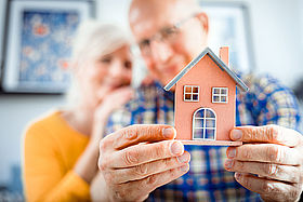 New house concept, happy senior couple holding small home model AIDE AU LOGEMENT POUR LES SENIORS
